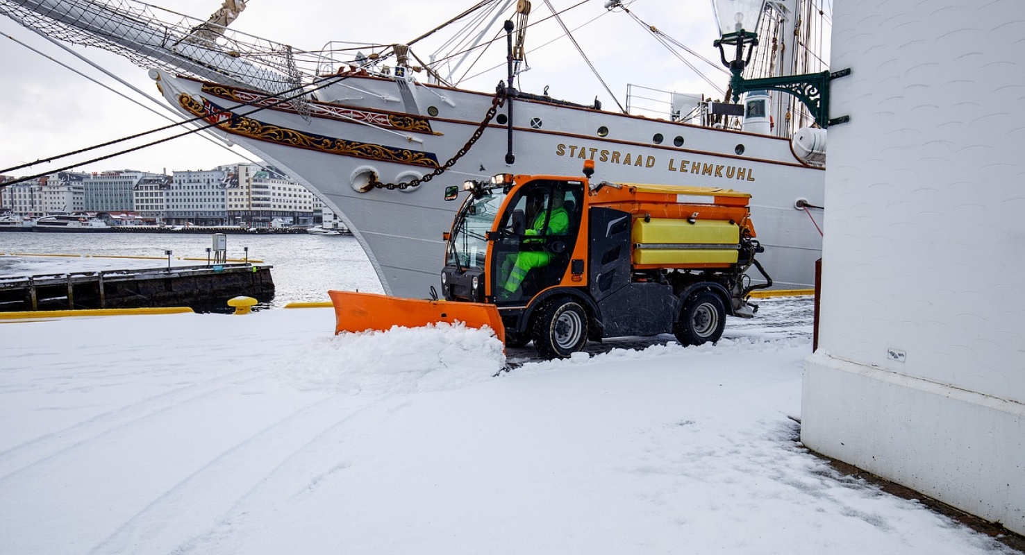 Een sneeuwschuiver maakt het terrein van een bedrijf sneeuwvrij.