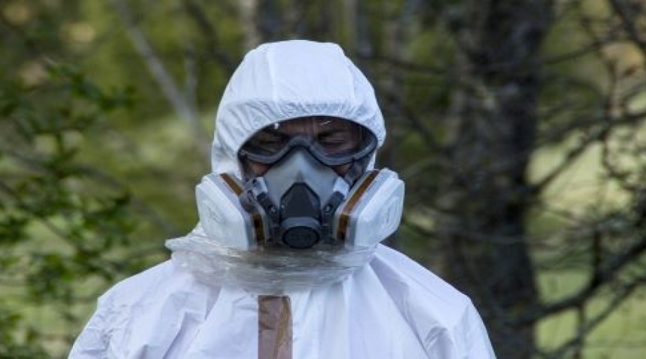 Een medewerker van een bedrijf dat asbest saneert, loopt in beschermende kleding.