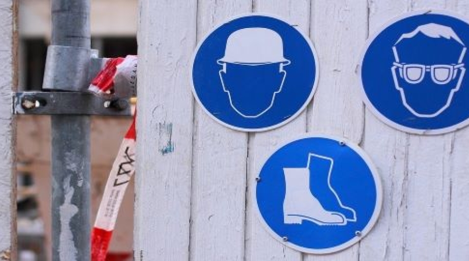Afbeelding van symbolen om veiligheidsvoorschriften op een werkplek te benadrukken. In dit geval een bouwhelm, veiligheidsbril en veiligheidsschoenen.