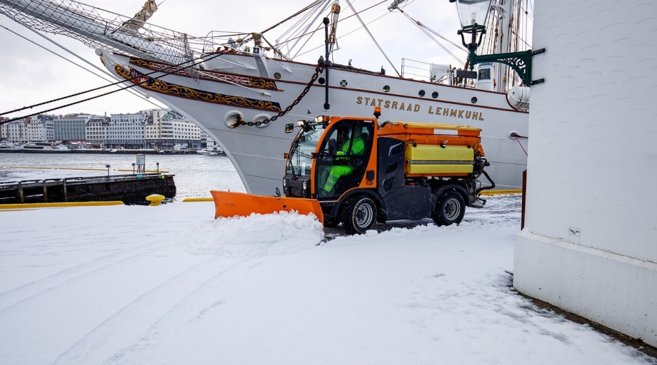 Een sneeuwschuiver maakt het terrein van een bedrijf sneeuwvrij.